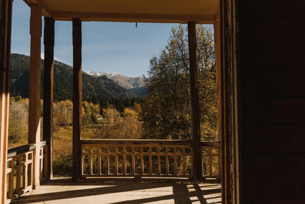 Serene autumn view of mountains from a rustic wooden veranda, capturing nature's beauty.